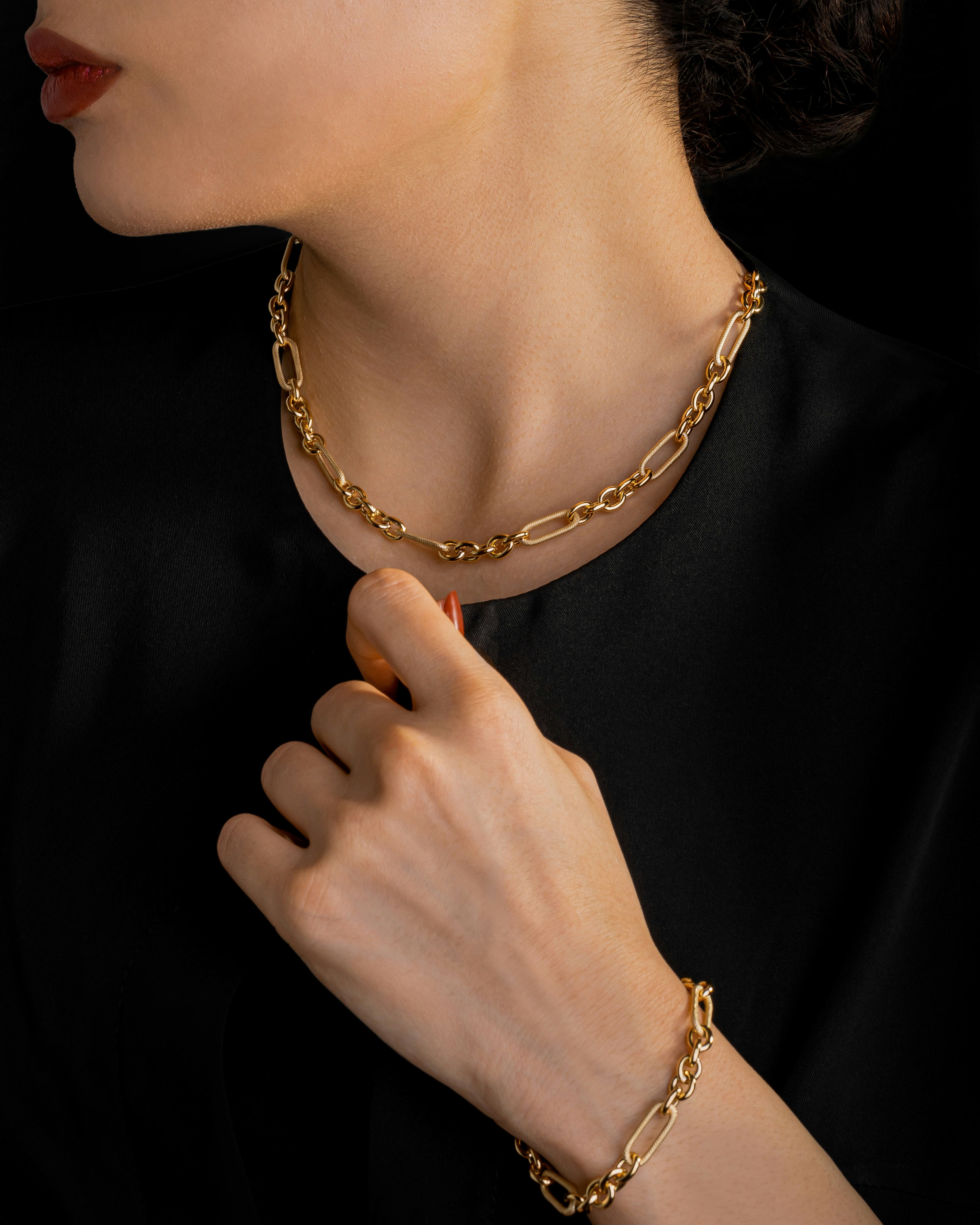 Model wearing a gold chain necklace and matching bracelet